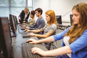 Computer teacher helping a pretty student in her class