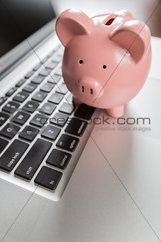 Piggy Bank Resting on Laptop Computer