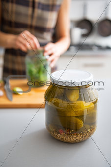 Closeup on jar of marinated cucumbers on table and housewife pic