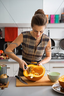 Young housewife removing filling from pumpkin