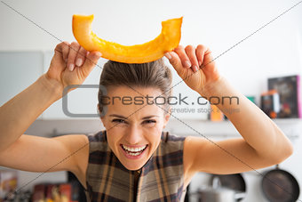 Happy young housewife having fun time using cutting pumpkin in k