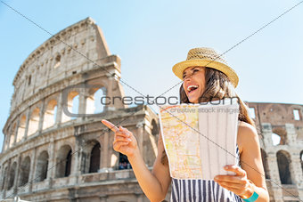 Happy young woman with map in front of colosseum in rome, italy 