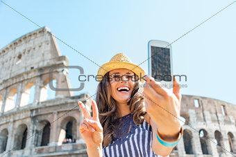 Happy young woman making selfie in front of colosseum in rome, i
