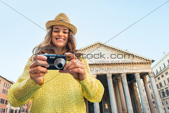 Portrait of happy young woman checking photos in camera in front