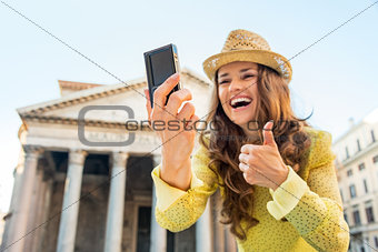 Closeup on happy young woman making selfie and showing thumbs up