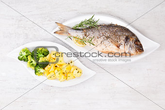 Grilled sea bream with potatoes on plate.