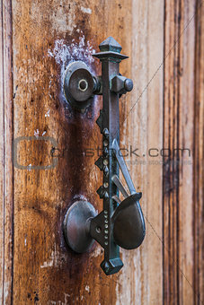 Old iron knoker on an old metal door