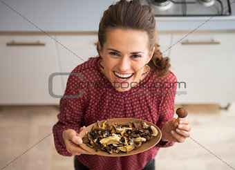 Happy young housewife showing mushrooms