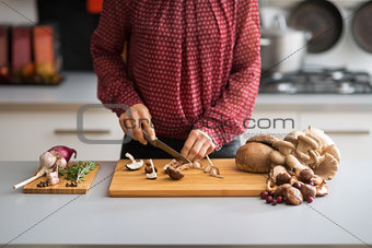 Closeup on young housewife cutting mushrooms