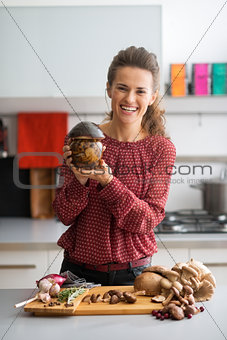 Happy young housewife showing jar of pickled mushrooms