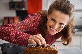 Happy young housewife decorating freshly baked pumpkin bread wit