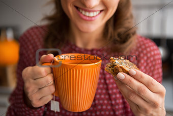 Closeup on young housewife drinking tea with freshly baked pumpk