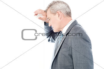Worried businessman leaning head on wall