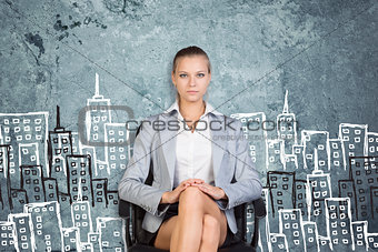 Businesswoman sitting against wall with sketch of city