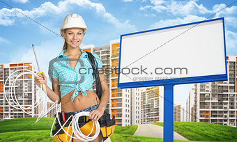 Woman in hard hat and tool belt holding coil of cable
