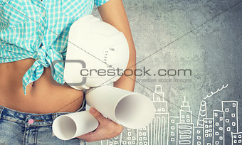Woman holding hard hat and drawing rolls 