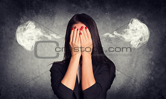 Close-up portrait of businesswoman hiding face in her hands, with smoke from ears
