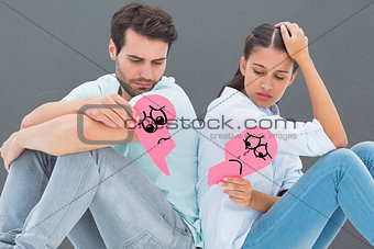 Composite image of sad couple sitting holding two halves of broken heart