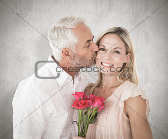 Composite image of affectionate man kissing his wife on the cheek with roses