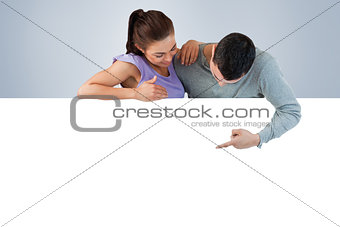 Composite image of young couple looking at wall below them
