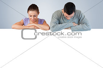 Composite image of young couple looking down to an advertisement