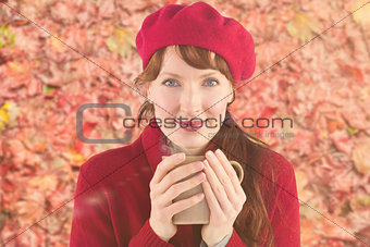 Composite image of woman holding a warm cup