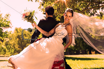 Newlywed couple sitting on scooter in park