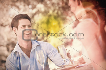 Couple with champagne flutes sitting at an outdoor café