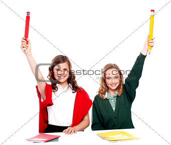 Students showing big pencil in raised arm
