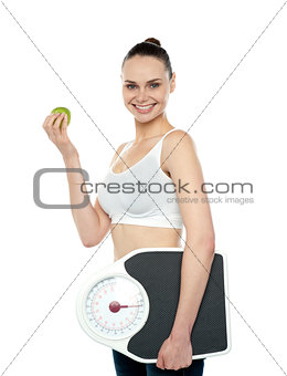 Attractive woman with apple and weight scale