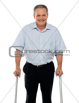 Senior man standing with support of crutches