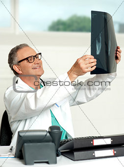 Aged surgeon holding patients x-ray report