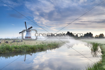 windmill and river in foggy morning