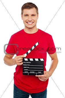 Smiling young guy holding clapperboard