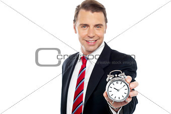 Smiling young consultant showing alarm clock