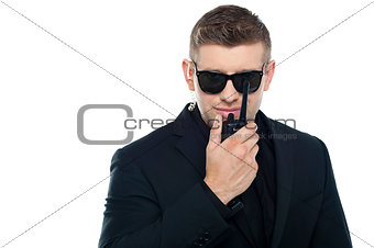 Smart young security personnel communicating over the walkie-talkie