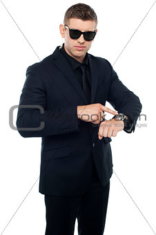 Security official pointing at his watch