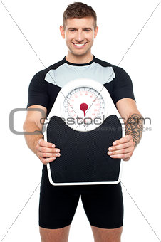 Smart young fit male showing weighing machine