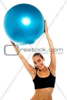 woman holding big blue pilates ball above her head