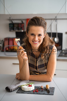 Portrait of happy young woman eating camembert