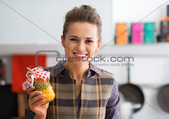 Portrait of happy young housewife showing jar with pickled veget