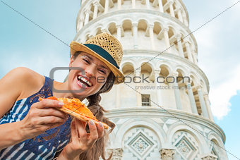 Portrait of happy young woman with pizza in front of leaning tow