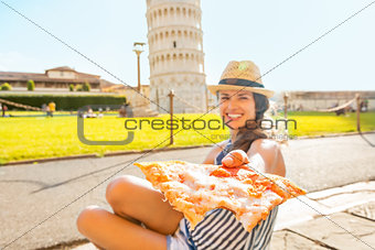 Closeup on young woman giving pizza in front of leaning tower of