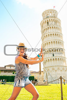 Funny young woman supporting leaning tower of pisa, tuscany, ita