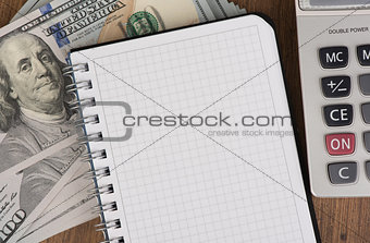 calculator and notepad lying on banknotes