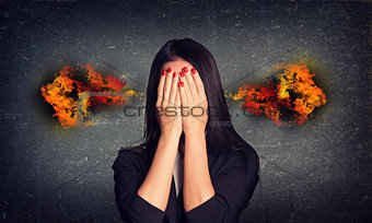 Crying woman with fire from ears. Concrete gray wall as backdrop