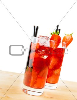 two glasses of strawberry cocktail with ice on light wood table 
