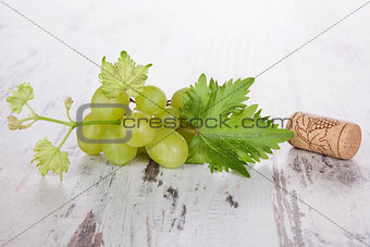 Wine bottle corks and leaves of grape isolated on white wooden b