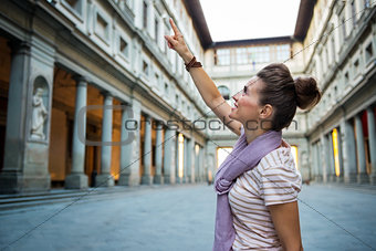 Young woman pointing near uffizi gallery in florence, italy