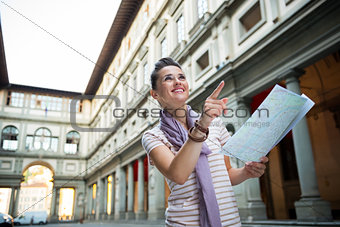 Happy young woman with map pointing near uffizi gallery in flore